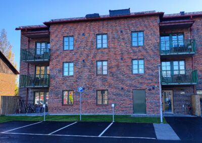 Sockenmagasinet: flerbostadshus med entré mot dess parkering – utrustat med cykelställ.
