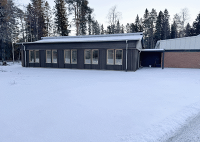 Ny tillbyggnad till Hörnefors församlingsgård med träfasad i vintermiljö.