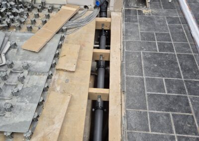 Öppet golv med synliga avloppsrör och kabeldragning under pågående installation.